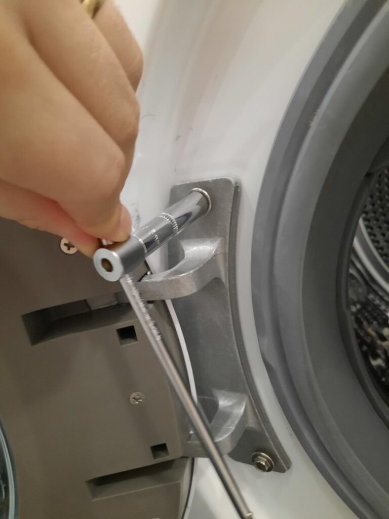 Odkręcenie uszkodzonych drzwi pralki LG SteamSpa F2J6QY0W za pomocą klucza nasadowego