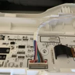 Podłączenia w pobliżu komory dolnej na proszek w pralce Samsung WW10T504DAE/S6